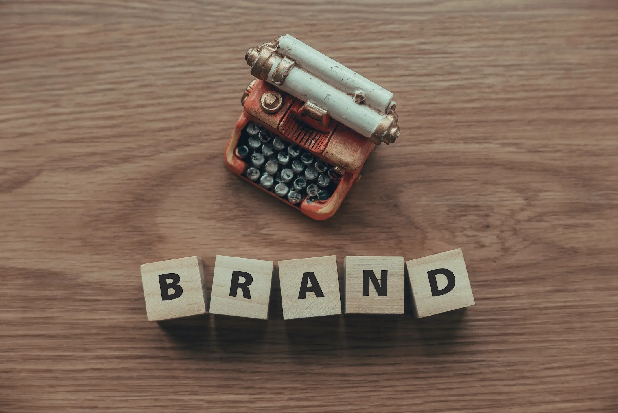 foto com uma máquina de escrever e a palavra "brand" escrita em cubos de letras - Como Escolher os Melhores Tipos de Marca para Seu Negócio?
